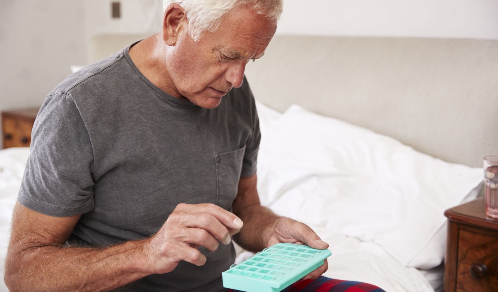 A senior man looking over his container of medications