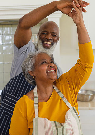 A senior couple dances while cooking together