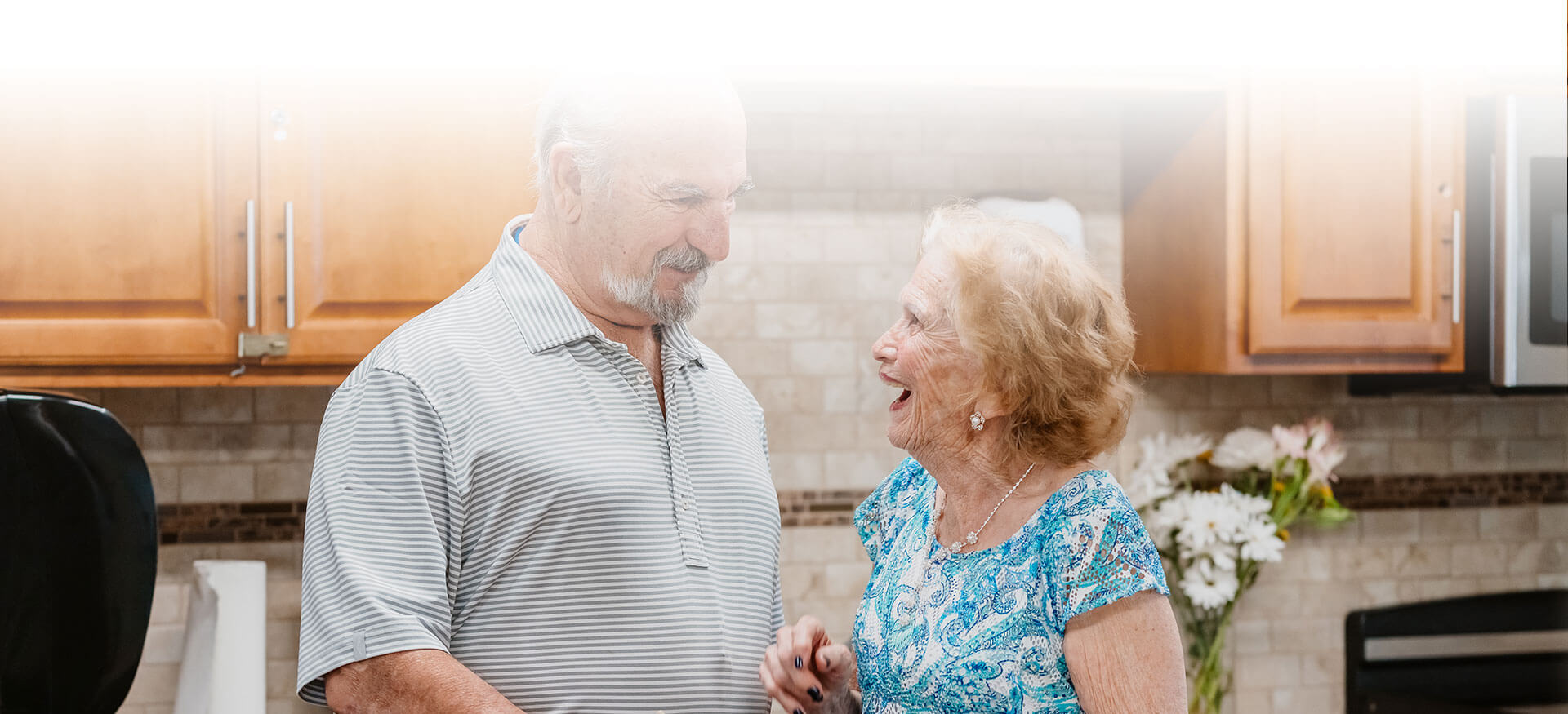 A senior couple laugh together in a kitchen
