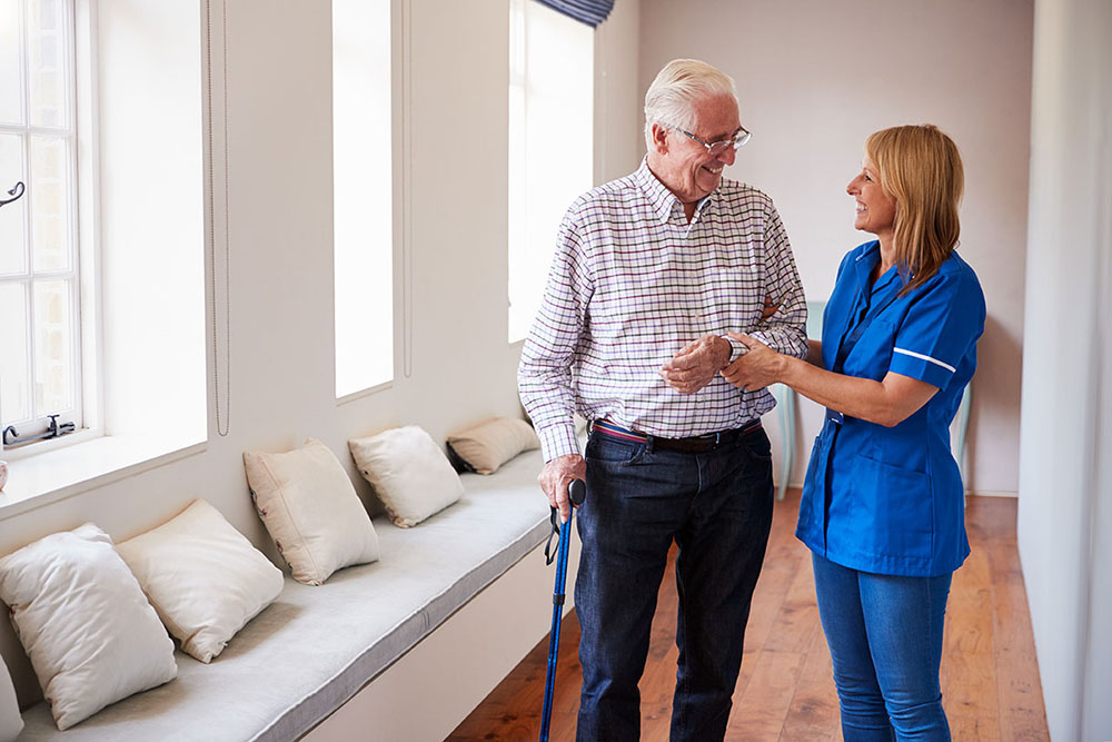 A senior man and his nurse take a walk through assisted living