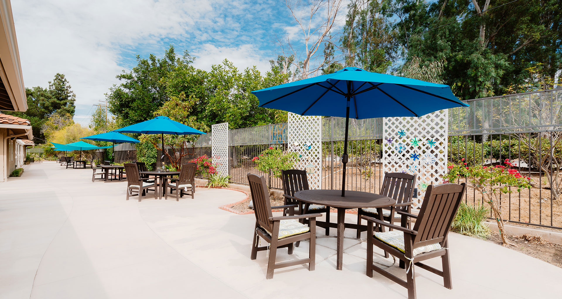 A bright outdoor patio space with patio tables, chair, and plants