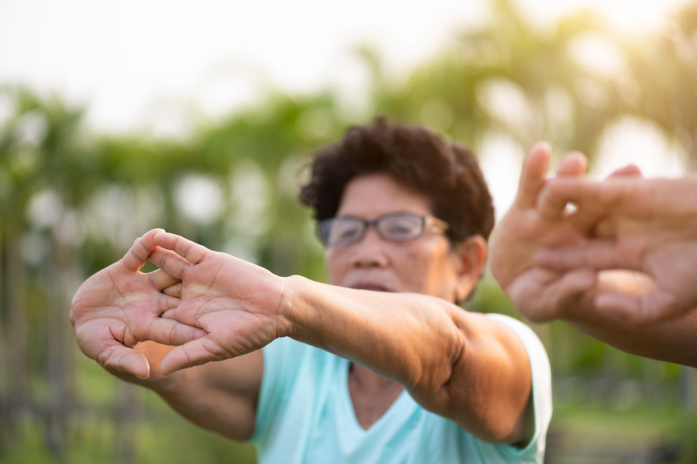 A senior woman stretches her hands