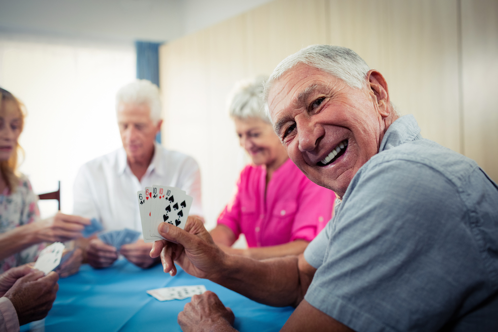A group of happy seniors playing a card game in their retirement community